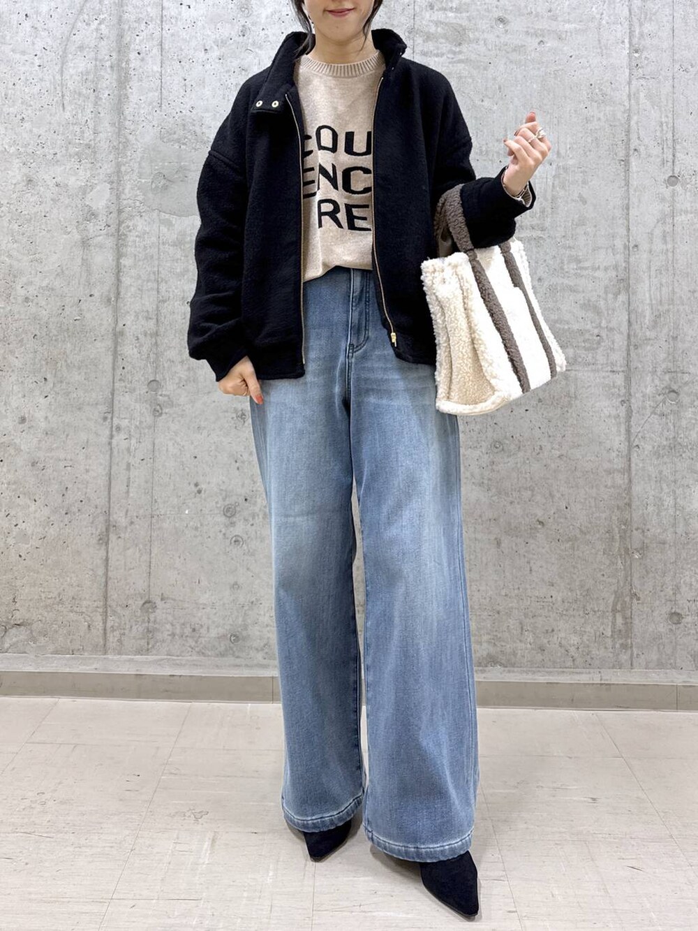 ベージュ系のニット/セーター、ブルー系のデニムパンツ、ブラック系のブルゾンを着用したレディースの秋コーディネートの2枚目の写真