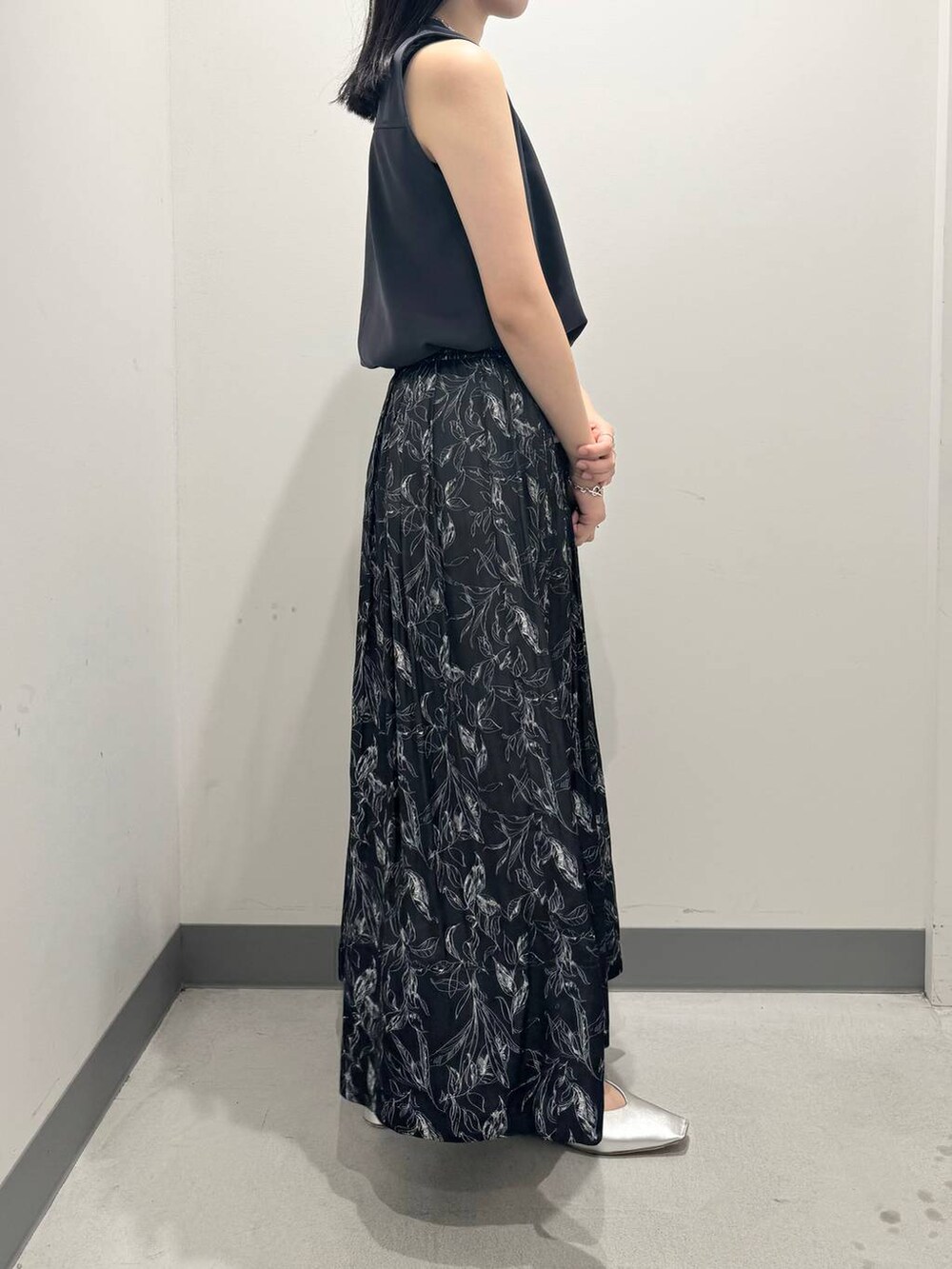 グレー系のTシャツ/カットソー、ブラック系のスカート、シルバー系のパンプスを着用したレディースの夏コーディネートの2枚目の写真