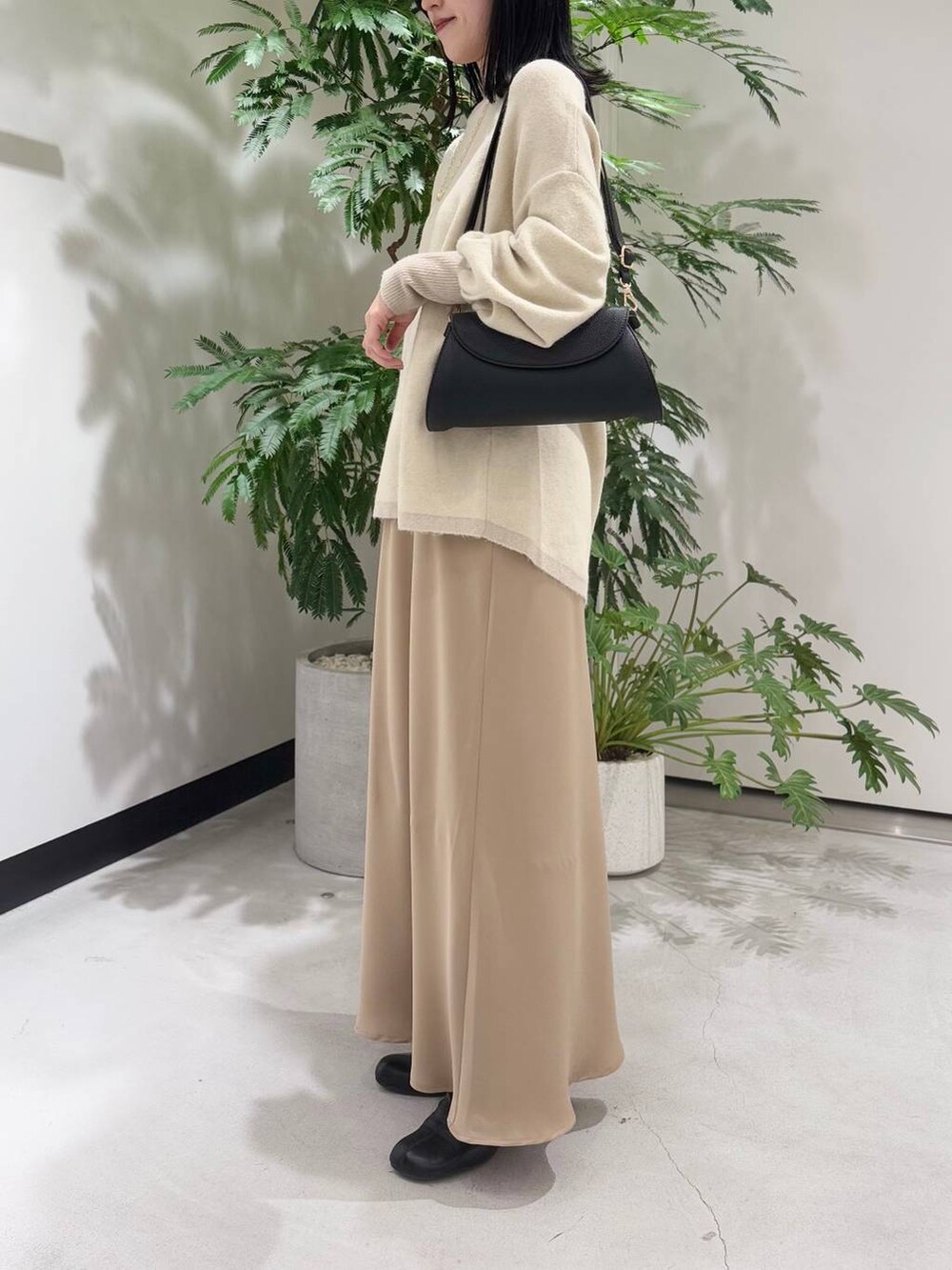 ブラック系のショルダーバッグ、ブラック系のブーツ、ホワイト系のニット/セーターを着用したレディースの冬コーディネートの2枚目の写真