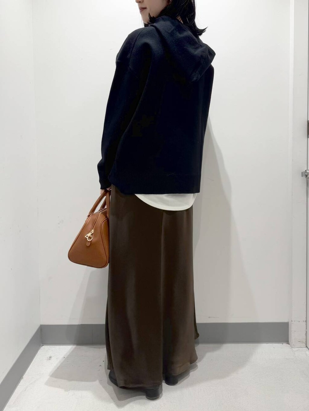 イエロー系のボストンバッグ、ブラック系のブーツ、ブラック系のニット/セーターを着用したレディースの冬コーディネートの3枚目の写真