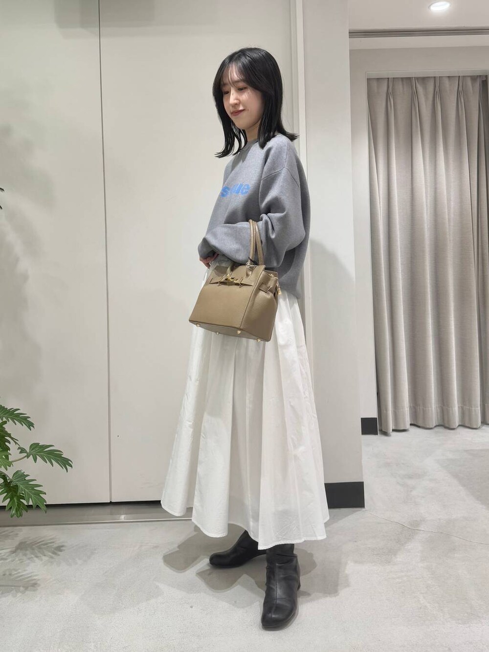 ホワイト系のスカート、ブラック系のブーツ、グレー系のニット/セーターを着用したレディースの冬コーディネートの2枚目の写真