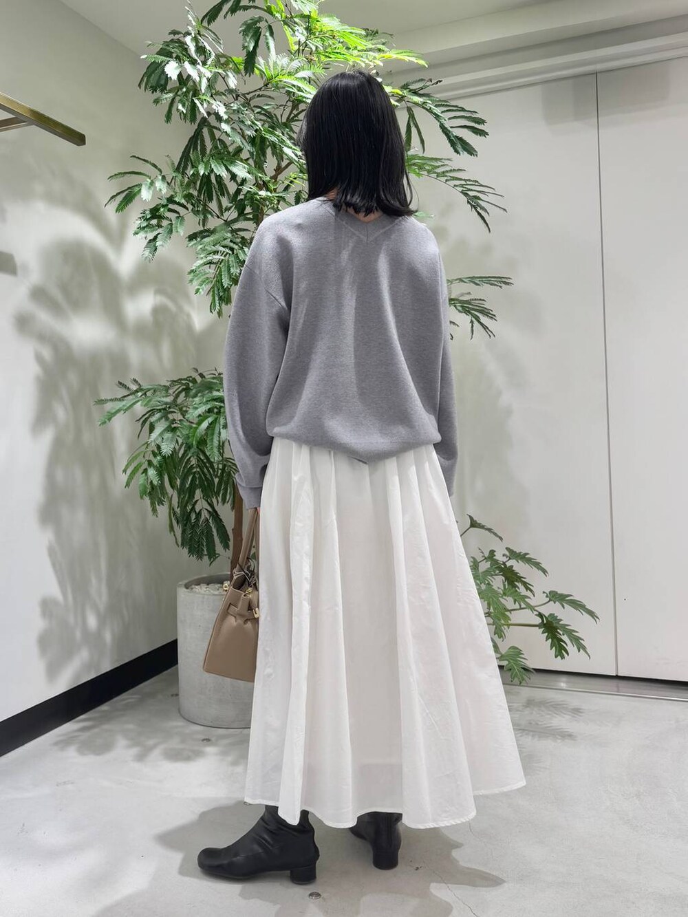 ホワイト系のスカート、ブラック系のブーツ、グレー系のニット/セーターを着用したレディースの冬コーディネートの3枚目の写真