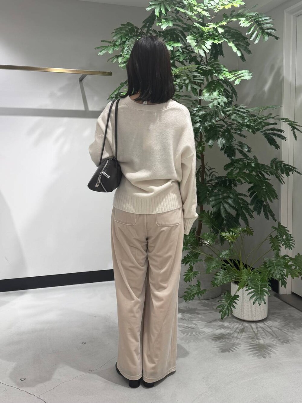 ブラック系のトートバッグ、ブラック系のブーツ、ホワイト系のニット/セーターを着用したレディースの冬コーディネートの3枚目の写真