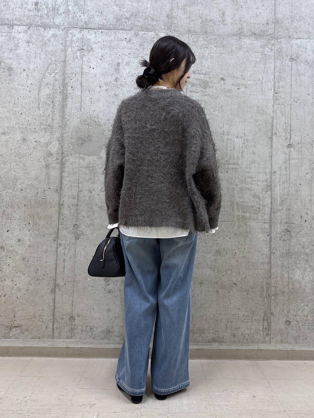 ブラック系のボストンバッグ、ホワイト系のシャツ/ブラウス、ブルー系のデニムパンツを着用したレディースの秋コーディネートの3枚目の写真