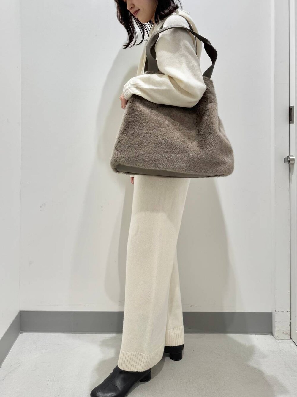 ホワイト系のニット/セーター、ブラウン系のトートバッグ、ホワイト系のその他パンツを着用したレディースの冬コーディネートの2枚目の写真