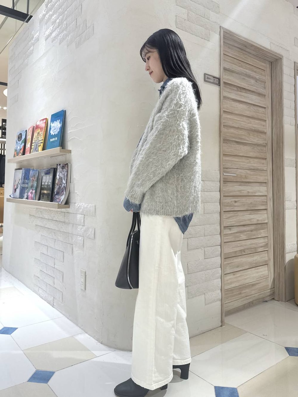 ブルー系のデニムパンツ、ブラウン系のトートバッグ、ブラック系のブーツを着用したレディースの秋コーディネートの2枚目の写真