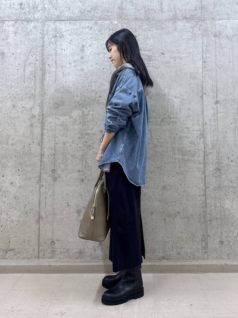 ブルー系のシャツ/ブラウス、ブラック系のブーツ、ブラウン系のボストンバッグを着用したレディースの秋コーディネートの2枚目の写真