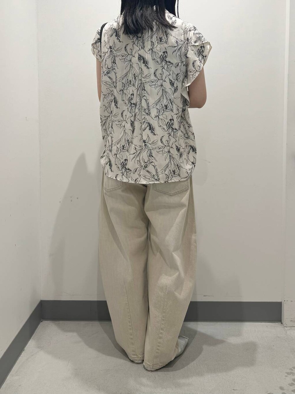 ブラック系のハンドバッグ、シルバー系のパンプス、ベージュ系のデニムパンツを着用したレディースの夏コーディネートの3枚目の写真