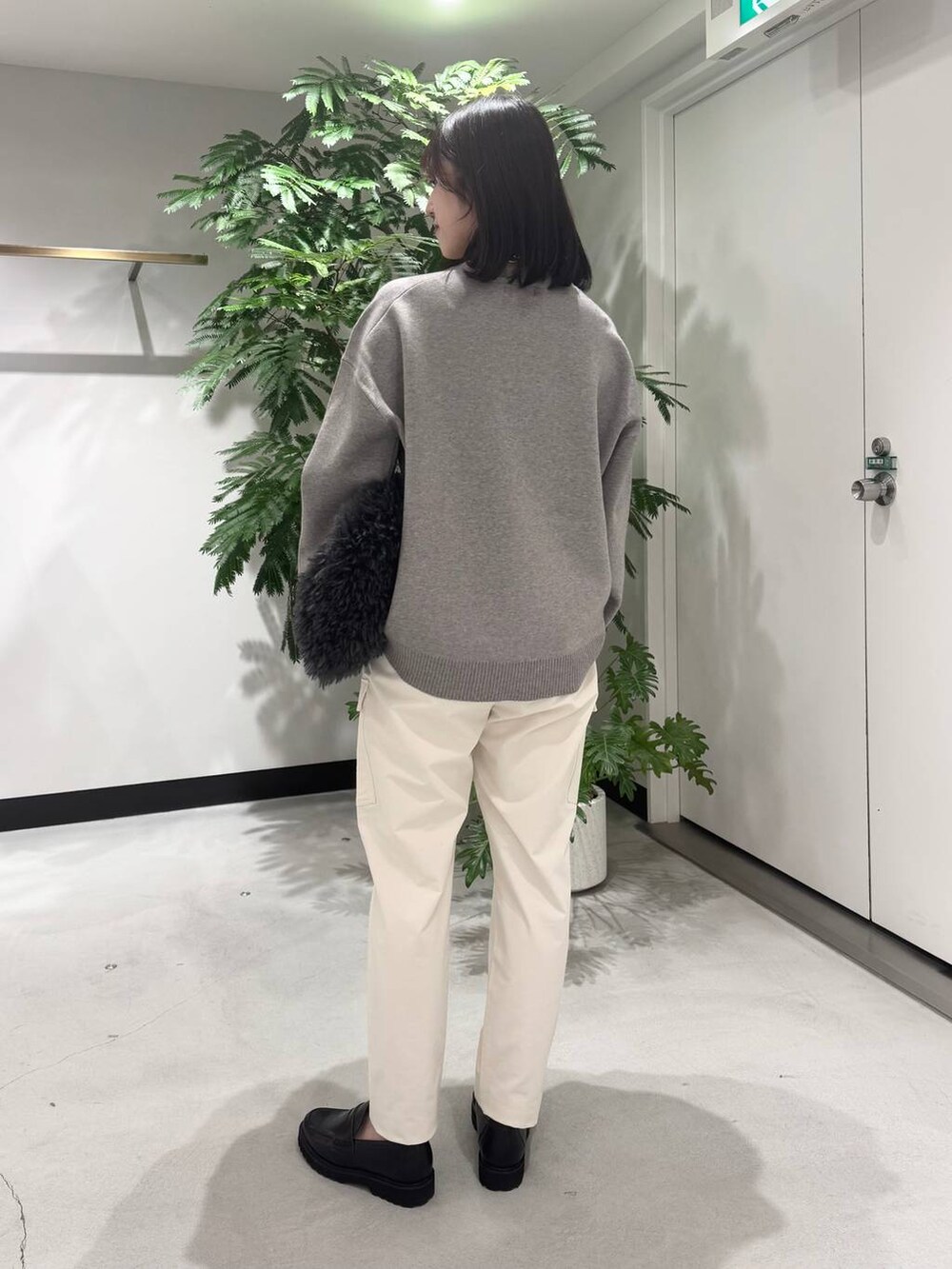 グレー系のトートバッグ、ブラック系のローファー、ホワイト系のカーゴパンツを着用したレディースの冬コーディネートの3枚目の写真