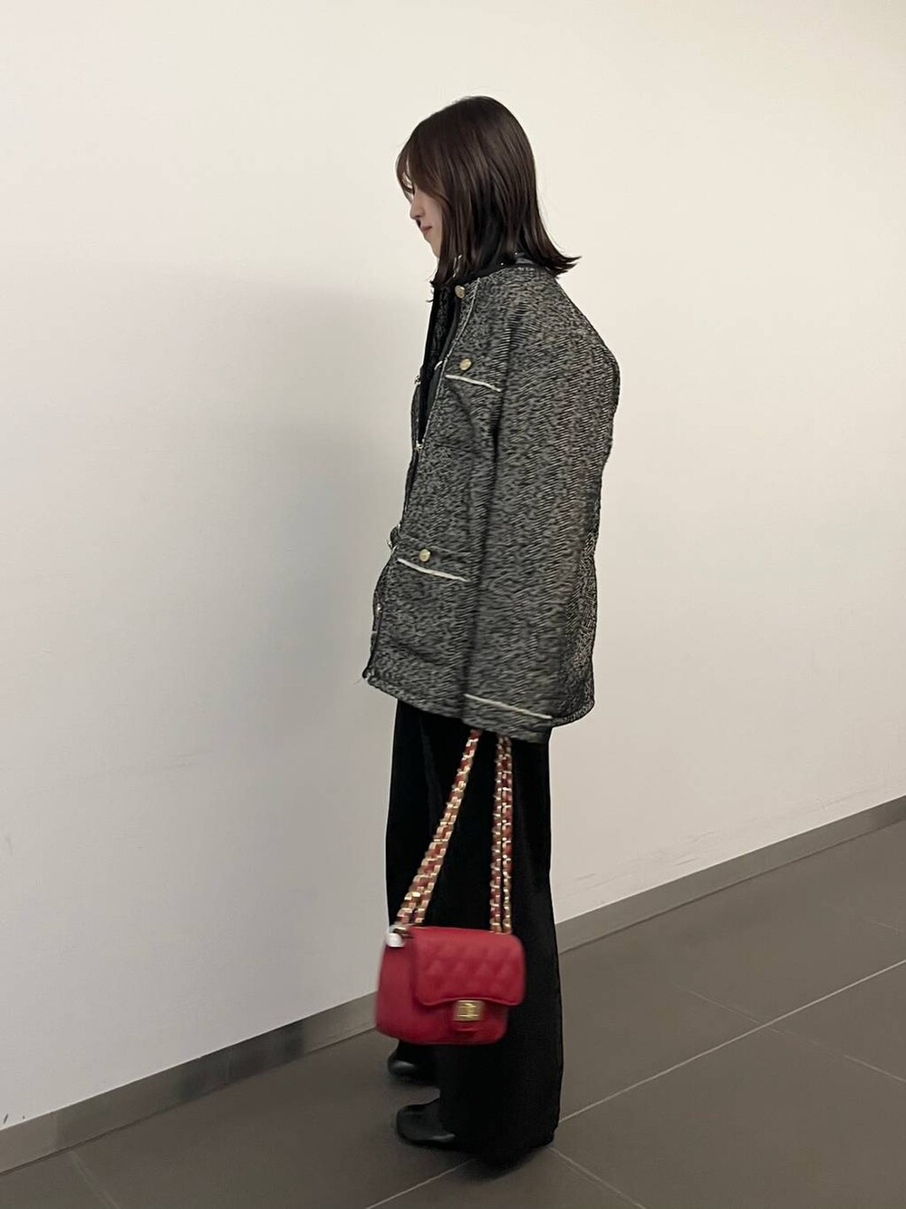 グレー系のニット/セーター、ブラック系のブーツ、ブラック系のノーカラーコートを着用したレディースの冬コーディネートの2枚目の写真