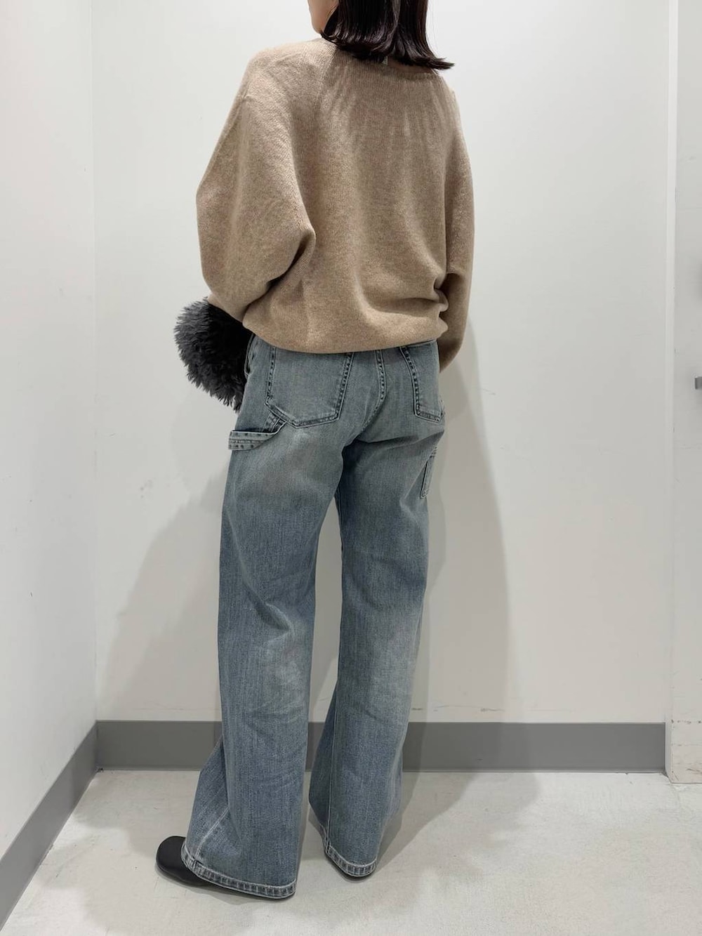 グレー系のトートバッグ、ブラック系のブーツ、ブルー系のデニムパンツを着用したレディースの冬コーディネートの3枚目の写真