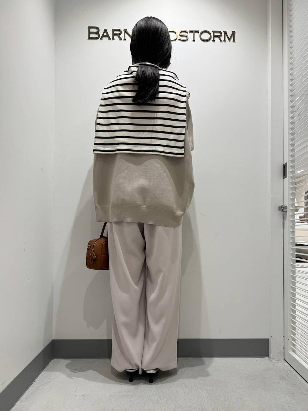 シルバー系のパンプス、イエロー系のスラックス、ブラウン系のハンドバッグを着用したレディースの冬コーディネートの3枚目の写真