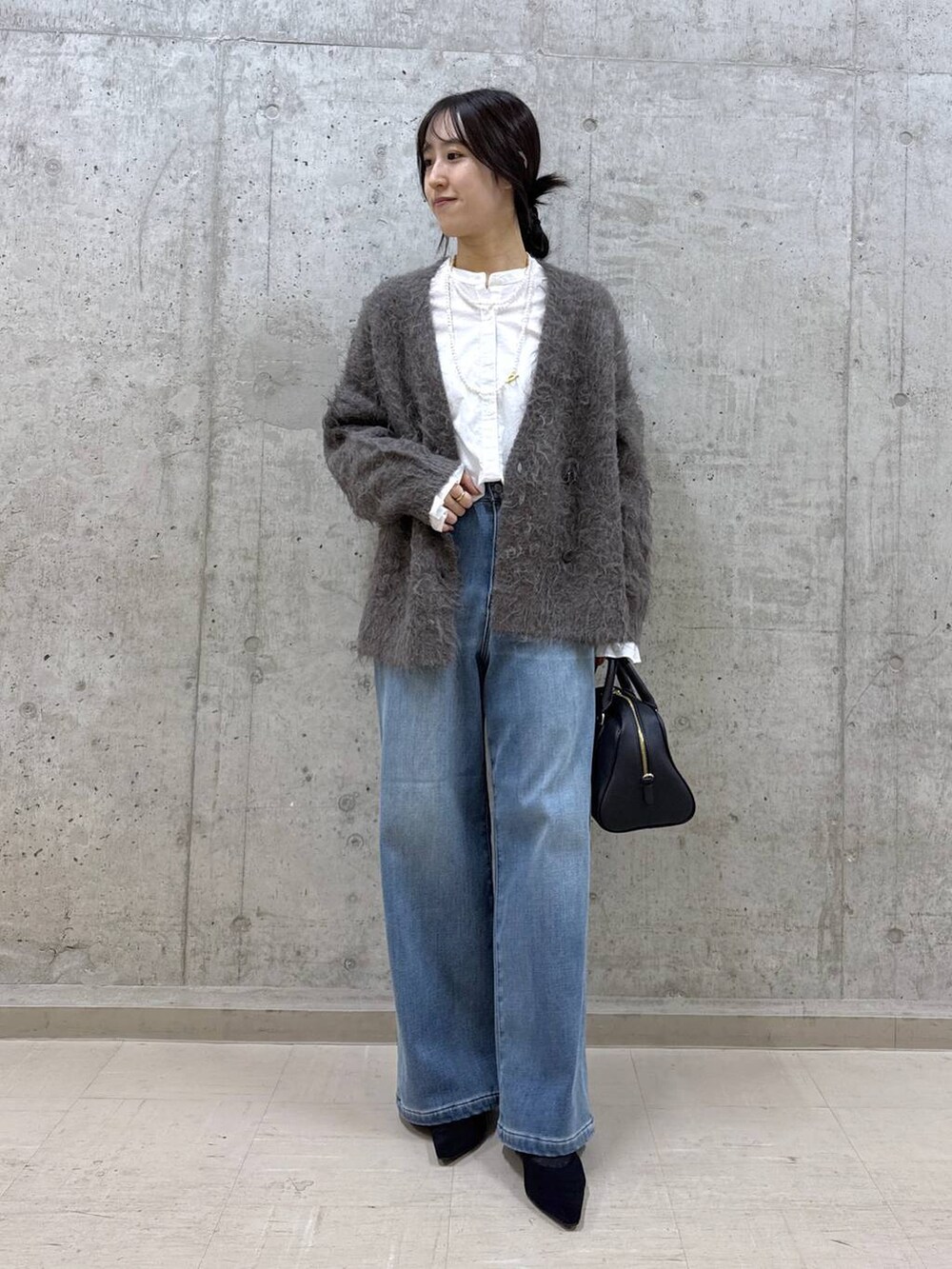 ブラック系のボストンバッグ、ホワイト系のシャツ/ブラウス、ブルー系のデニムパンツを着用したレディースの秋コーディネートの4枚目の写真