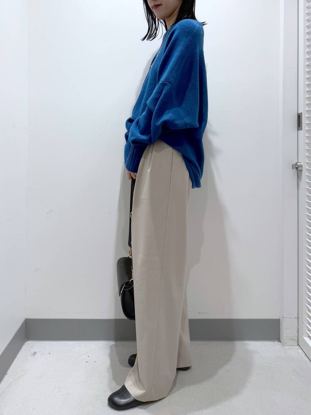 ブラック系のショルダーバッグ、ブラック系のブーツ、ブルー系のニット/セーターを着用したレディースの冬コーディネートの2枚目の写真