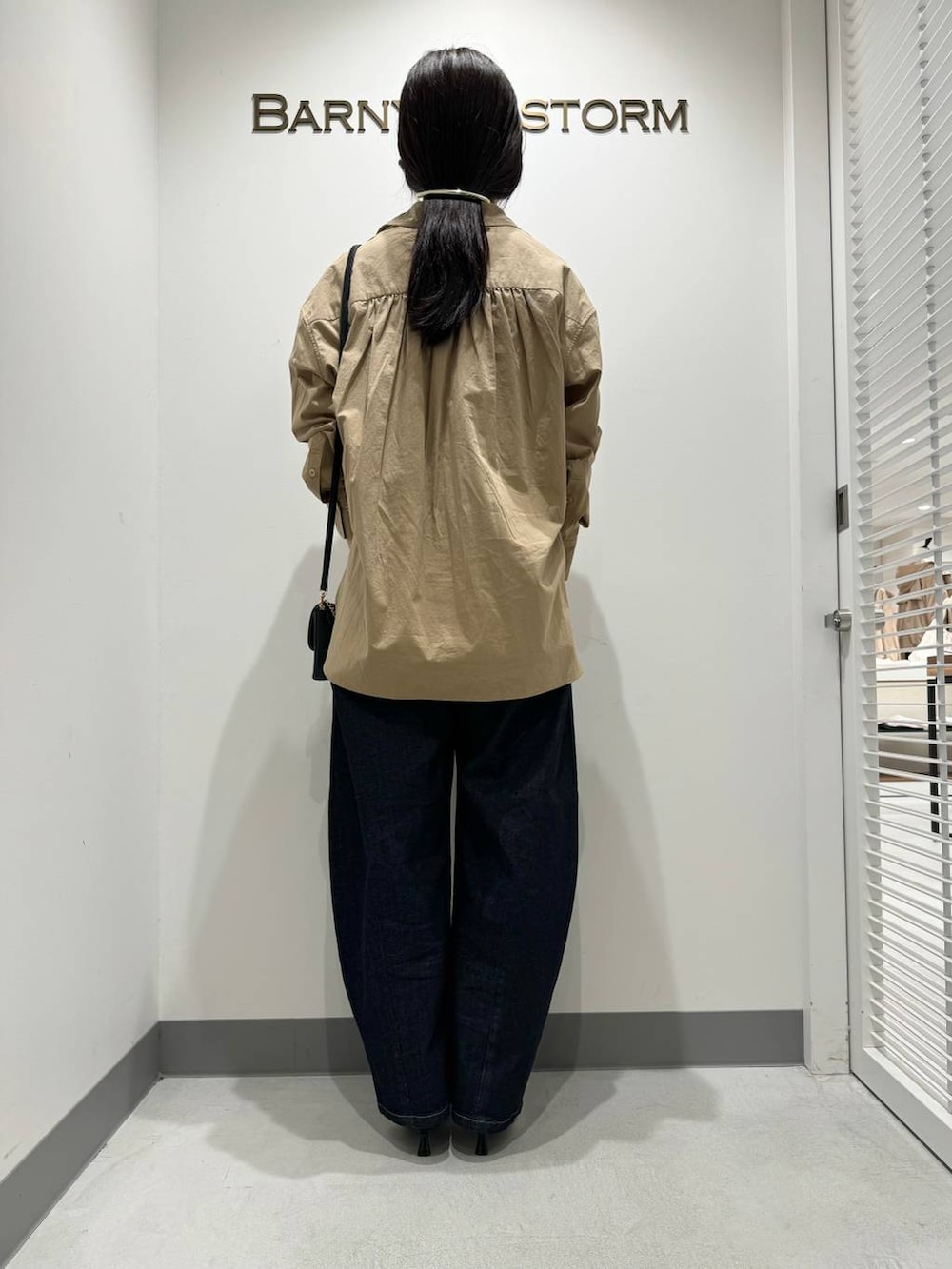 シルバー系のパンプス、ブルー系のデニムパンツ、ブラック系のショルダーバッグを着用したレディースの冬コーディネートの3枚目の写真