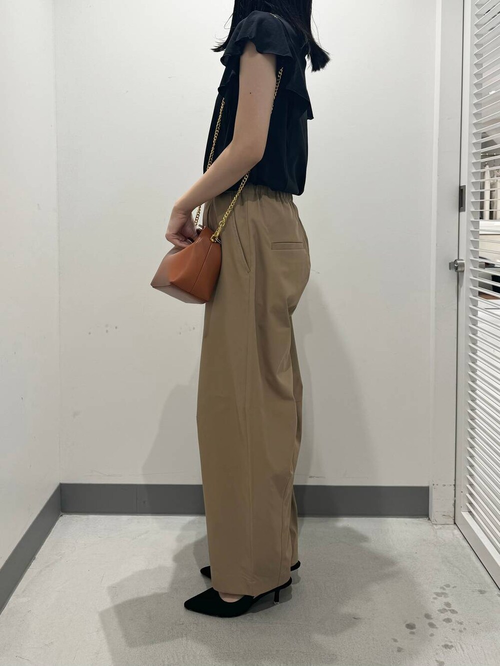 ブラウン系のショルダーバッグ、ブラック系のTシャツ/カットソー、ベージュ系のその他パンツを着用したレディースの夏コーディネートの2枚目の写真