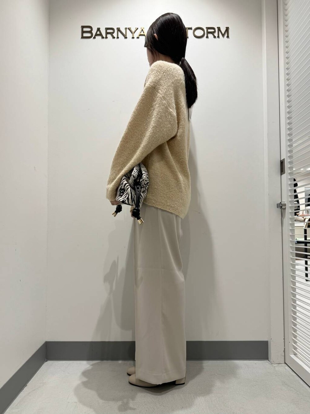 ホワイト系のブーツ、ホワイト系のスラックス、その他のショルダーバッグを着用したレディースの冬コーディネートの2枚目の写真