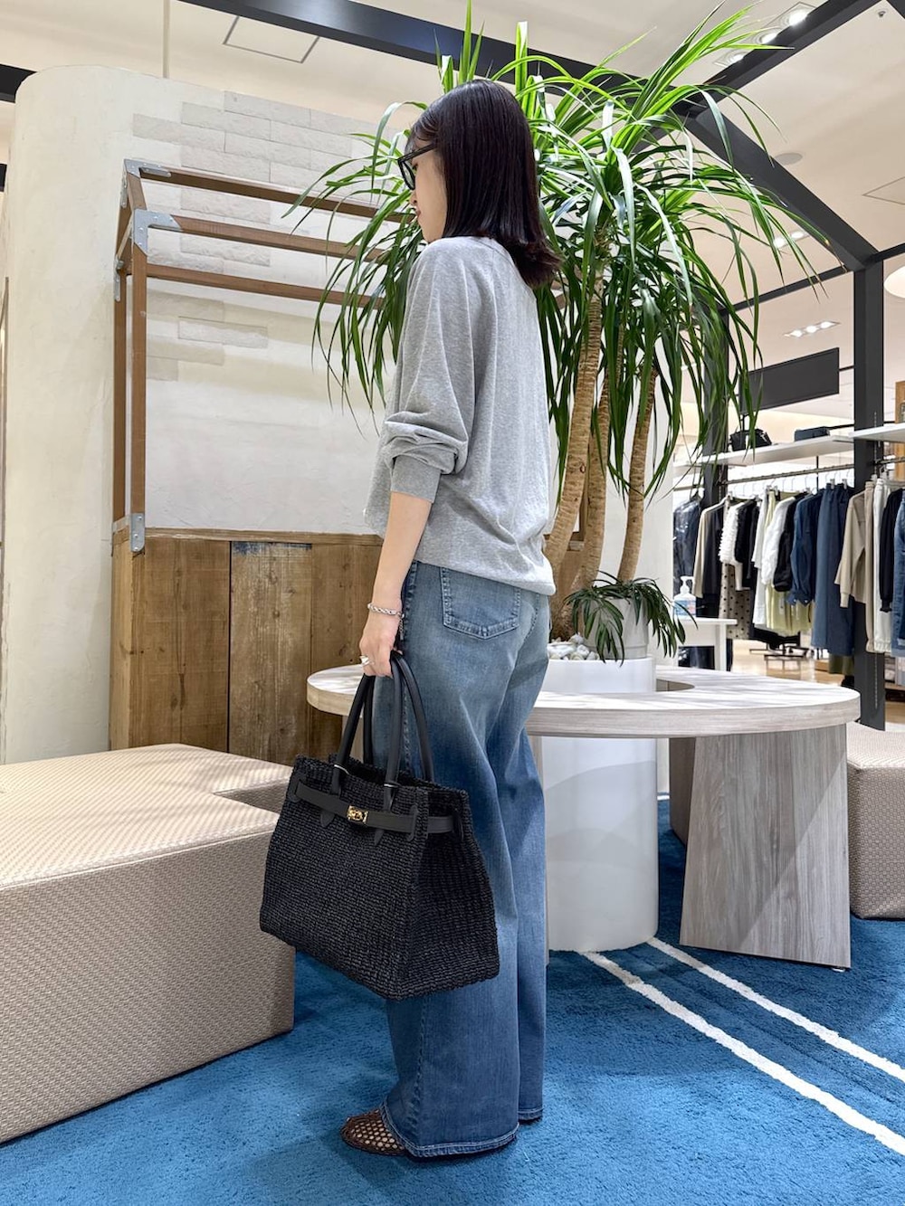 グレー系のニット/セーター、ブルー系のデニムパンツ、ブラウン系のスリッポンを着用したレディースの春コーディネートの2枚目の写真
