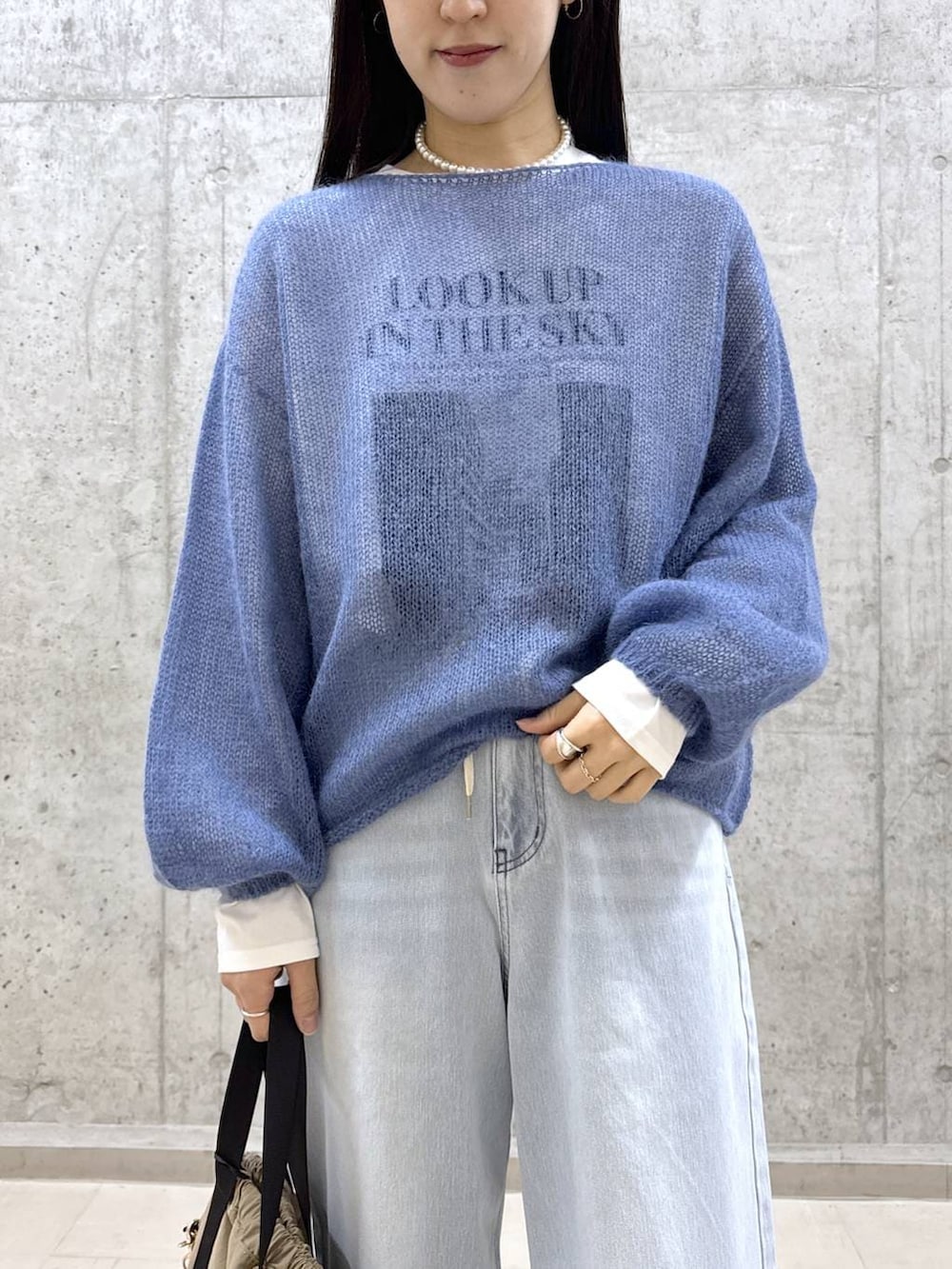 ブルー系のデニムパンツ、ブルー系のニット/セーター、ホワイト系のTシャツ/カットソーを着用したレディースの冬コーディネートの4枚目の写真