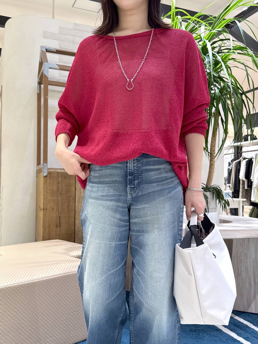 ホワイト系のトートバッグ、ブルー系のデニムパンツ、レッド系のニット/セーターを着用したレディースの春コーディネートの3枚目の写真