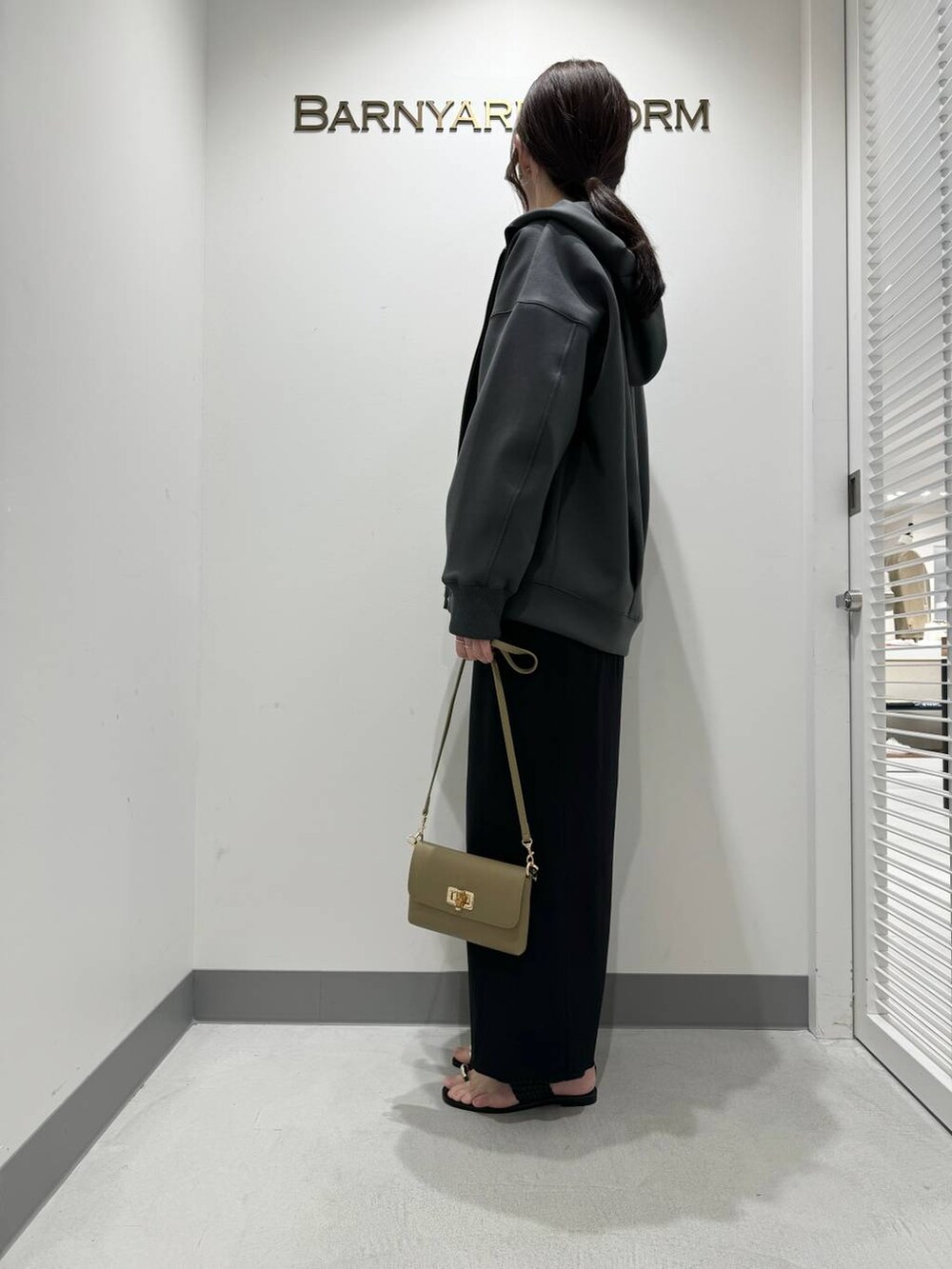 ブラック系のサンダル、グレー系のパーカー、ベージュ系のショルダーバッグを着用したレディースの春コーディネートの2枚目の写真