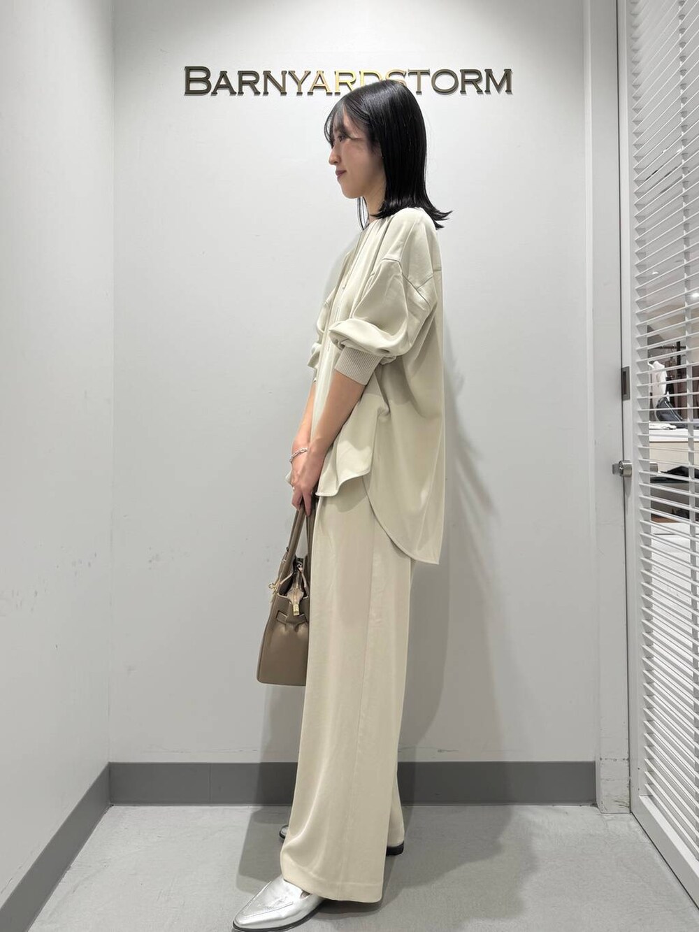 シルバー系のローファー、ベージュ系のショルダーバッグ、ホワイト系のシャツ/ブラウスを着用したレディースの冬コーディネートの2枚目の写真