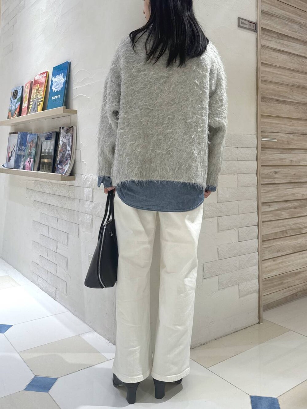 ブルー系のデニムパンツ、ブラウン系のトートバッグ、ブラック系のブーツを着用したレディースの秋コーディネートの3枚目の写真