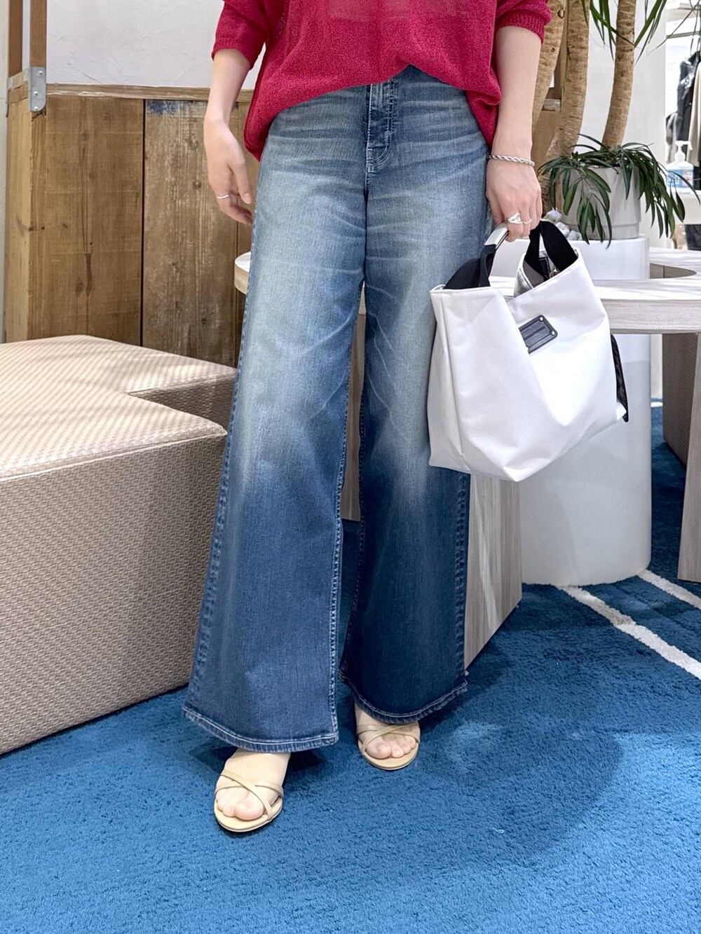 ホワイト系のトートバッグ、ブルー系のデニムパンツ、レッド系のニット/セーターを着用したレディースの春コーディネートの4枚目の写真