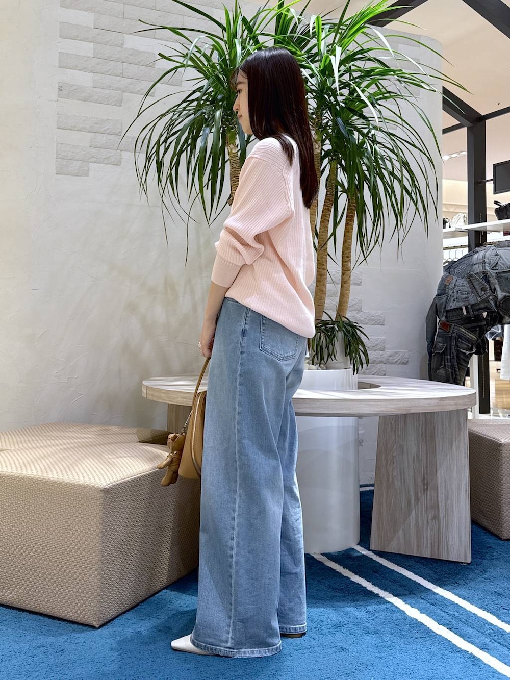 ブルー系のデニムパンツ、ブラウン系のトートバッグ、ホワイト系のキャミソールを着用したレディースの冬コーディネートの2枚目の写真