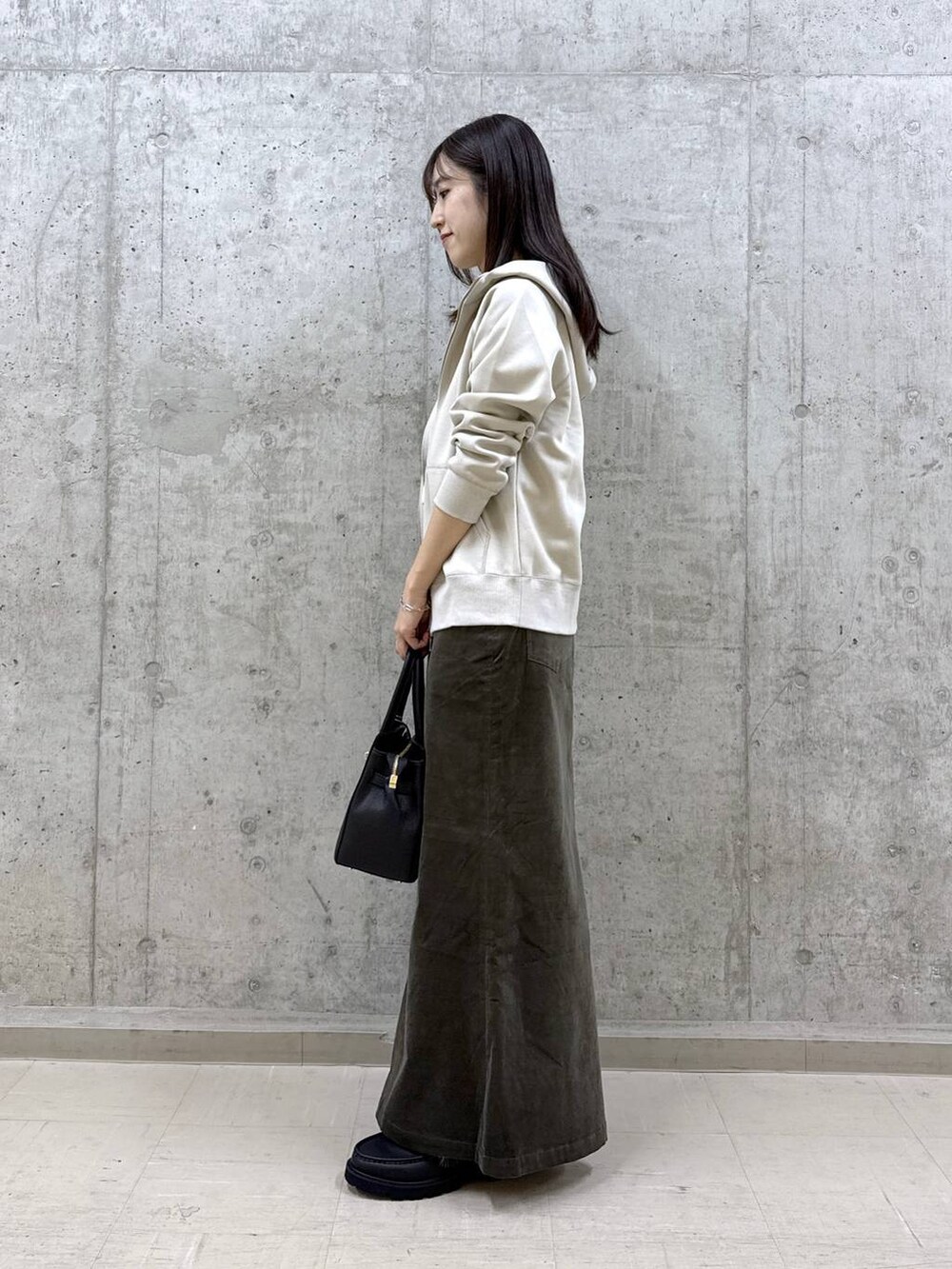 ブラック系のショルダーバッグ、ホワイト系のTシャツ/カットソー、ブラウン系のスカートを着用したレディースの秋コーディネートの3枚目の写真