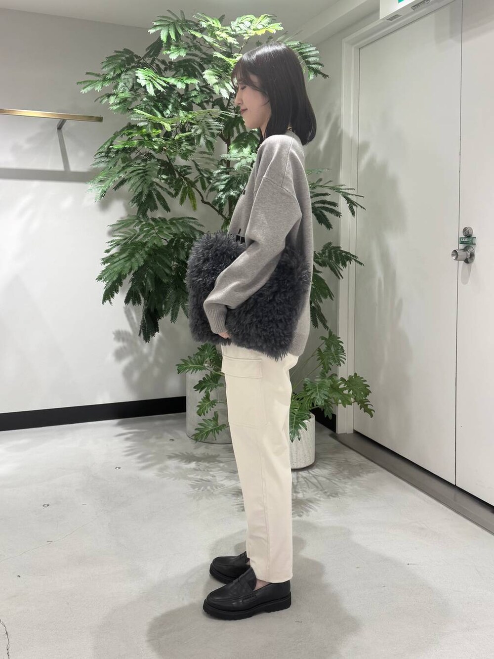 グレー系のトートバッグ、ブラック系のローファー、ホワイト系のカーゴパンツを着用したレディースの冬コーディネートの2枚目の写真