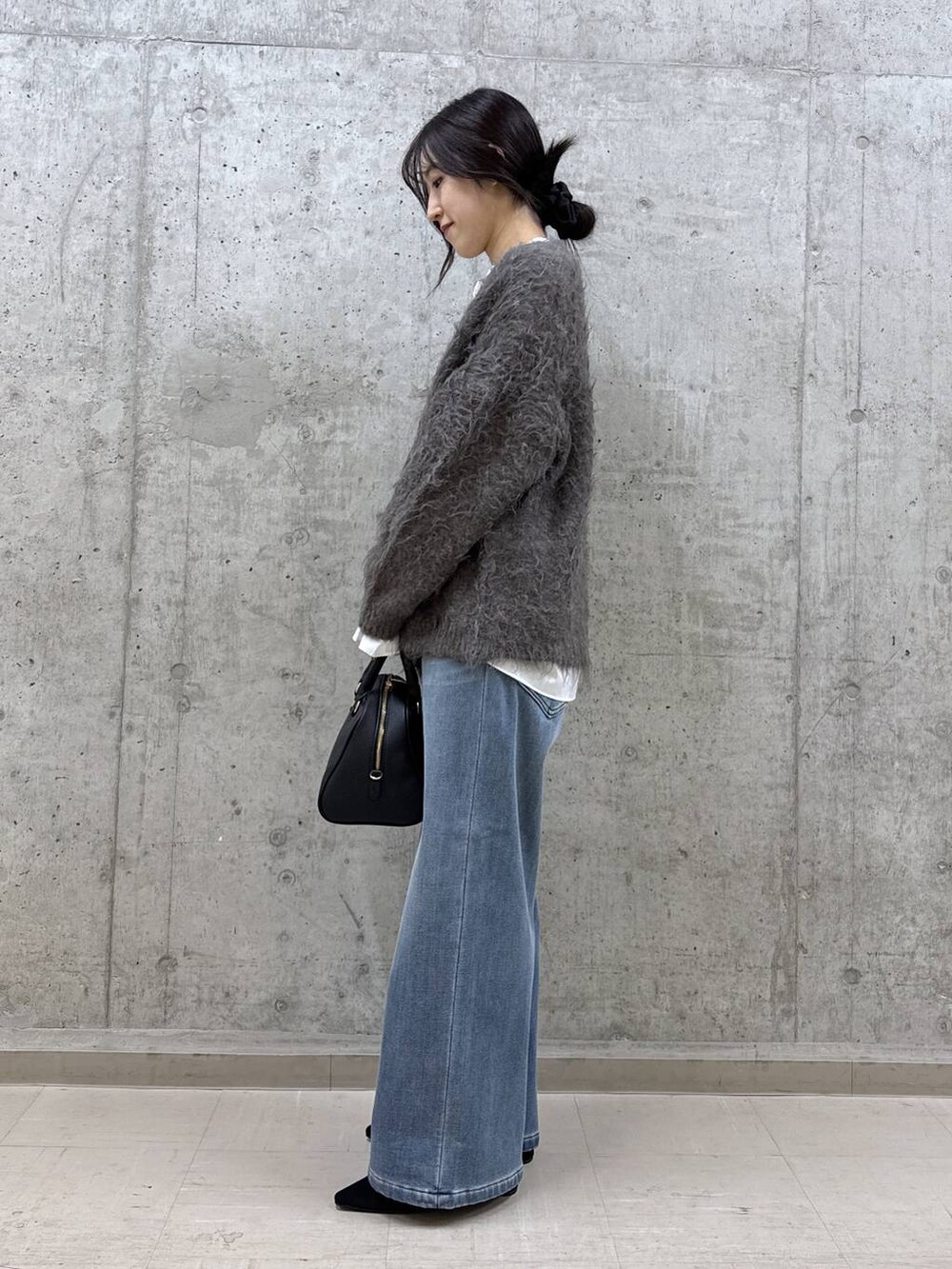 ブラック系のボストンバッグ、ホワイト系のシャツ/ブラウス、ブルー系のデニムパンツを着用したレディースの秋コーディネートの2枚目の写真