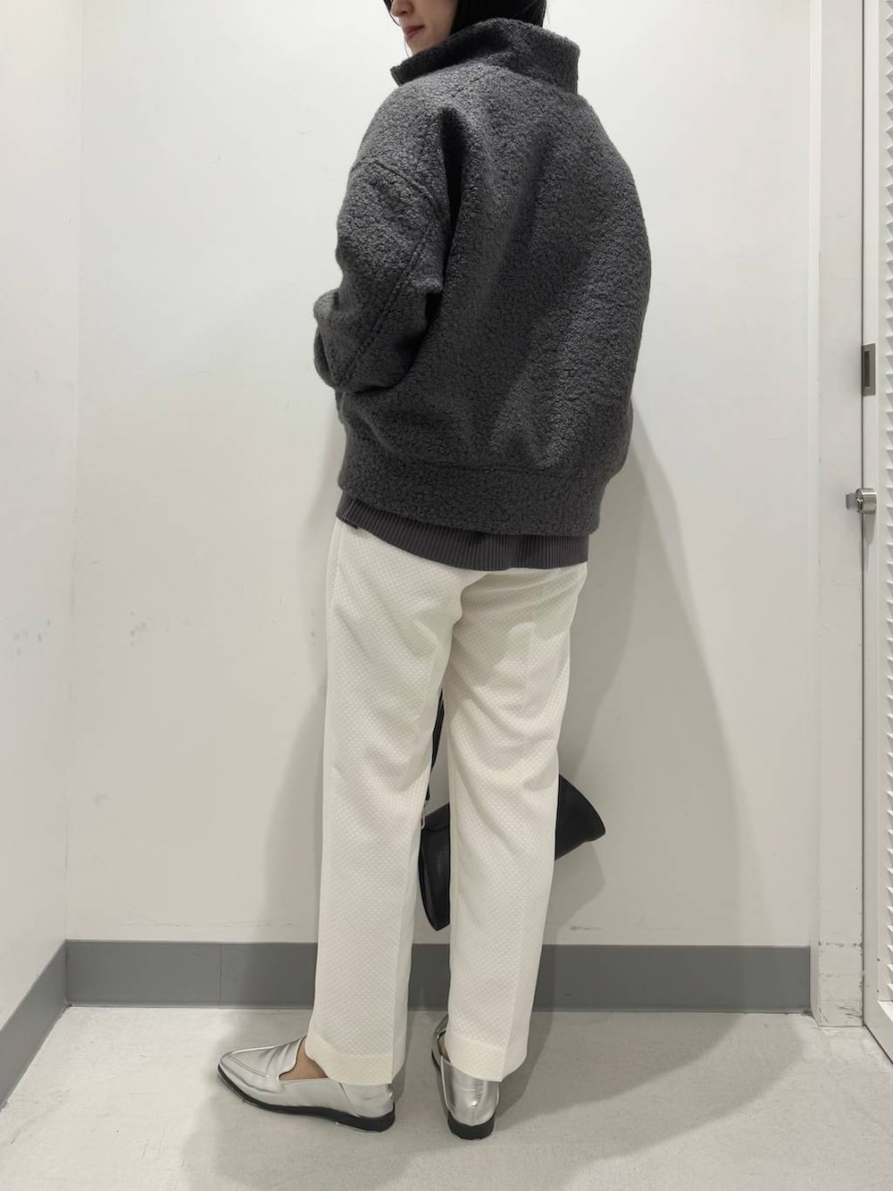 シルバー系のローファー、ブラック系のショルダーバッグ、グレー系のニット/セーターを着用したレディースの冬コーディネートの3枚目の写真