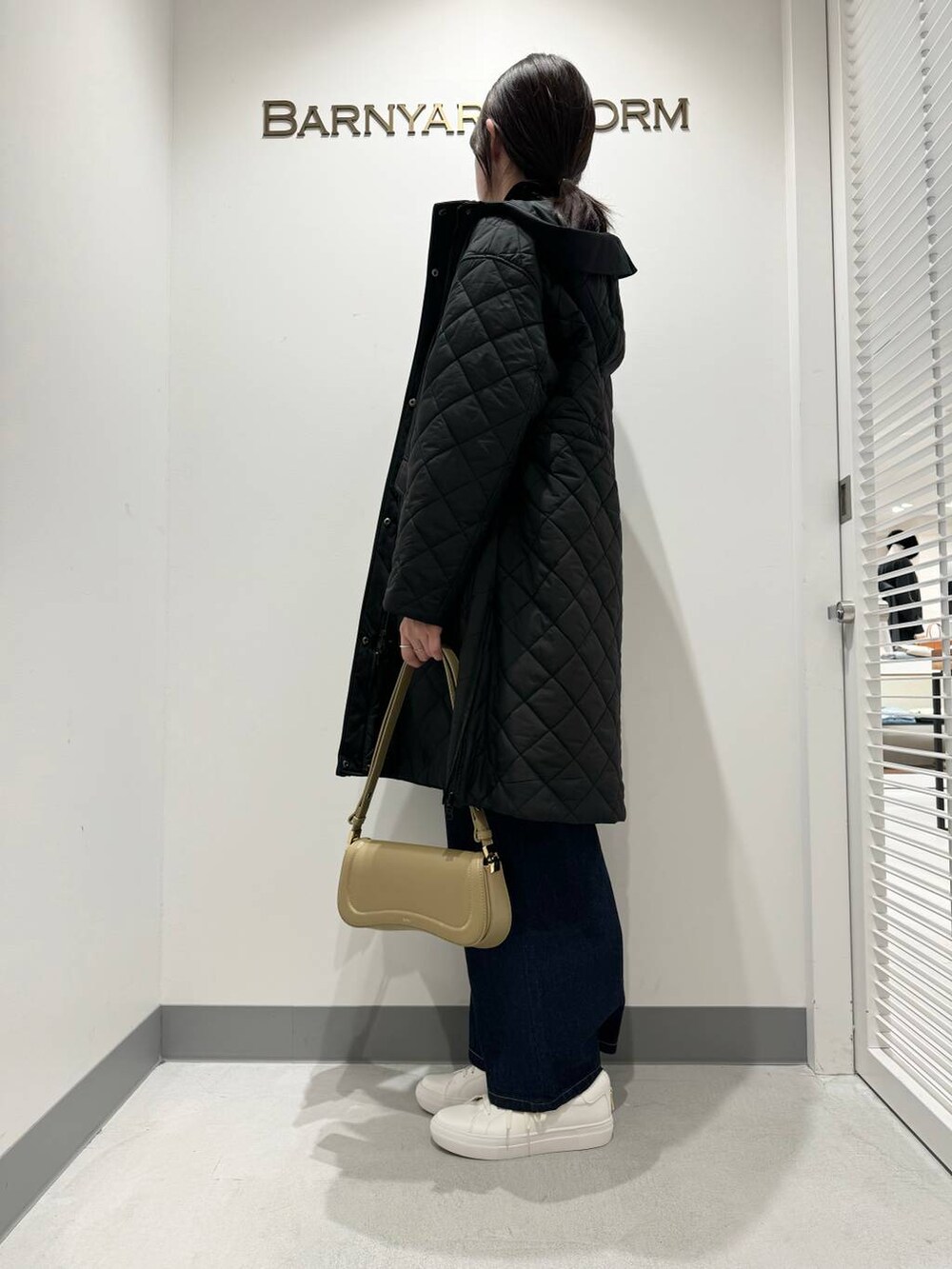 ブラック系のニット/セーター、ベージュ系のショルダーバッグ、ブラック系のダウンジャケット/コートを着用したレディースの冬コーディネートの2枚目の写真