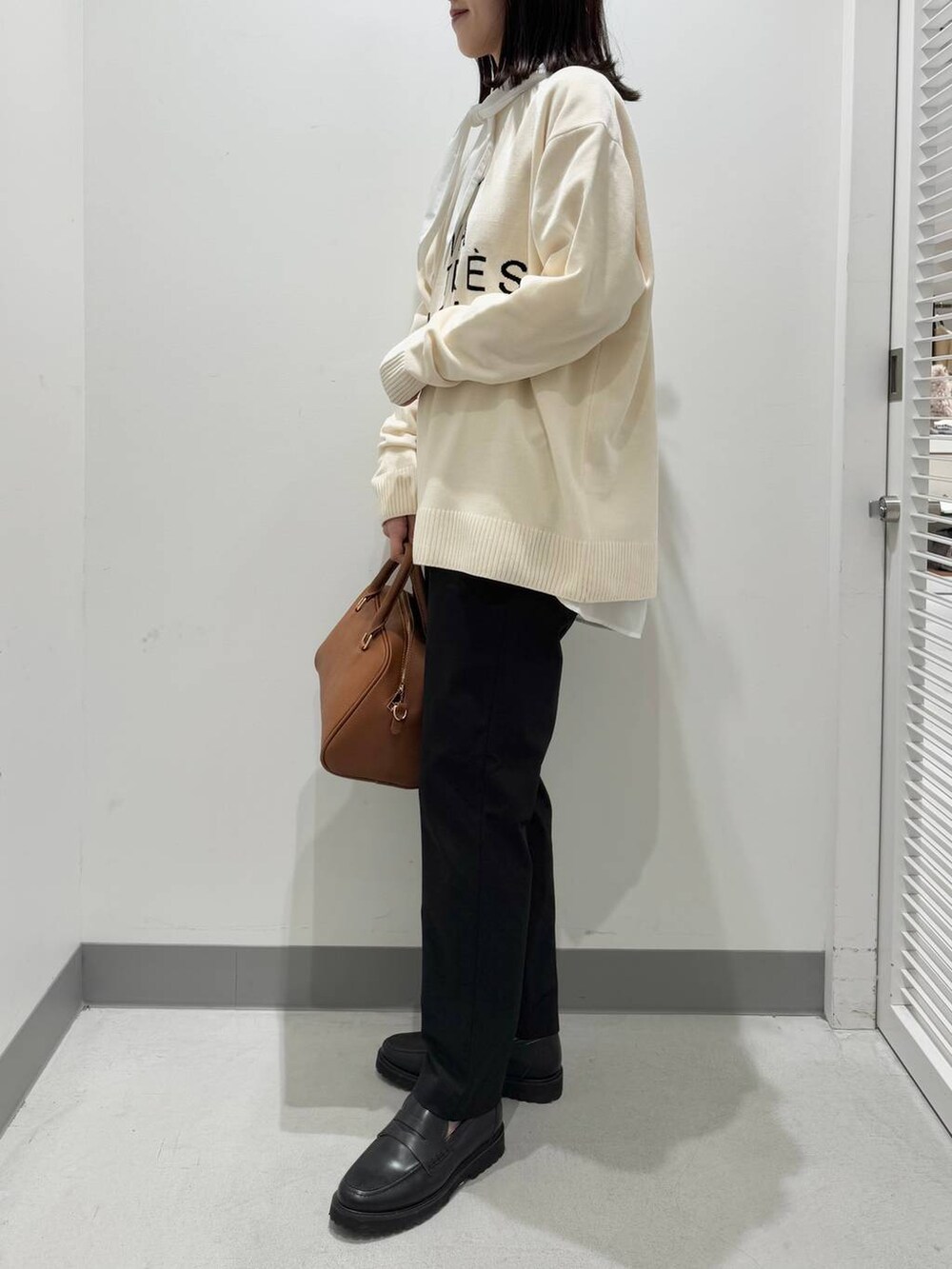 ホワイト系のニット/セーター、ホワイト系のシャツ/ブラウス、イエロー系のボストンバッグを着用したレディースの冬コーディネートの2枚目の写真