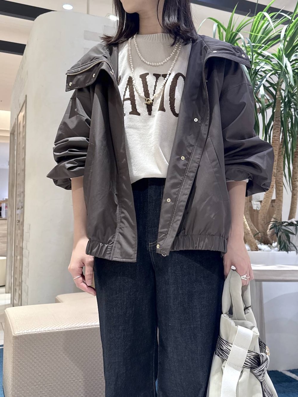 グレー系のトートバッグ、ブルー系のデニムパンツ、ホワイト系のニット/セーターを着用したレディースの秋コーディネートの4枚目の写真