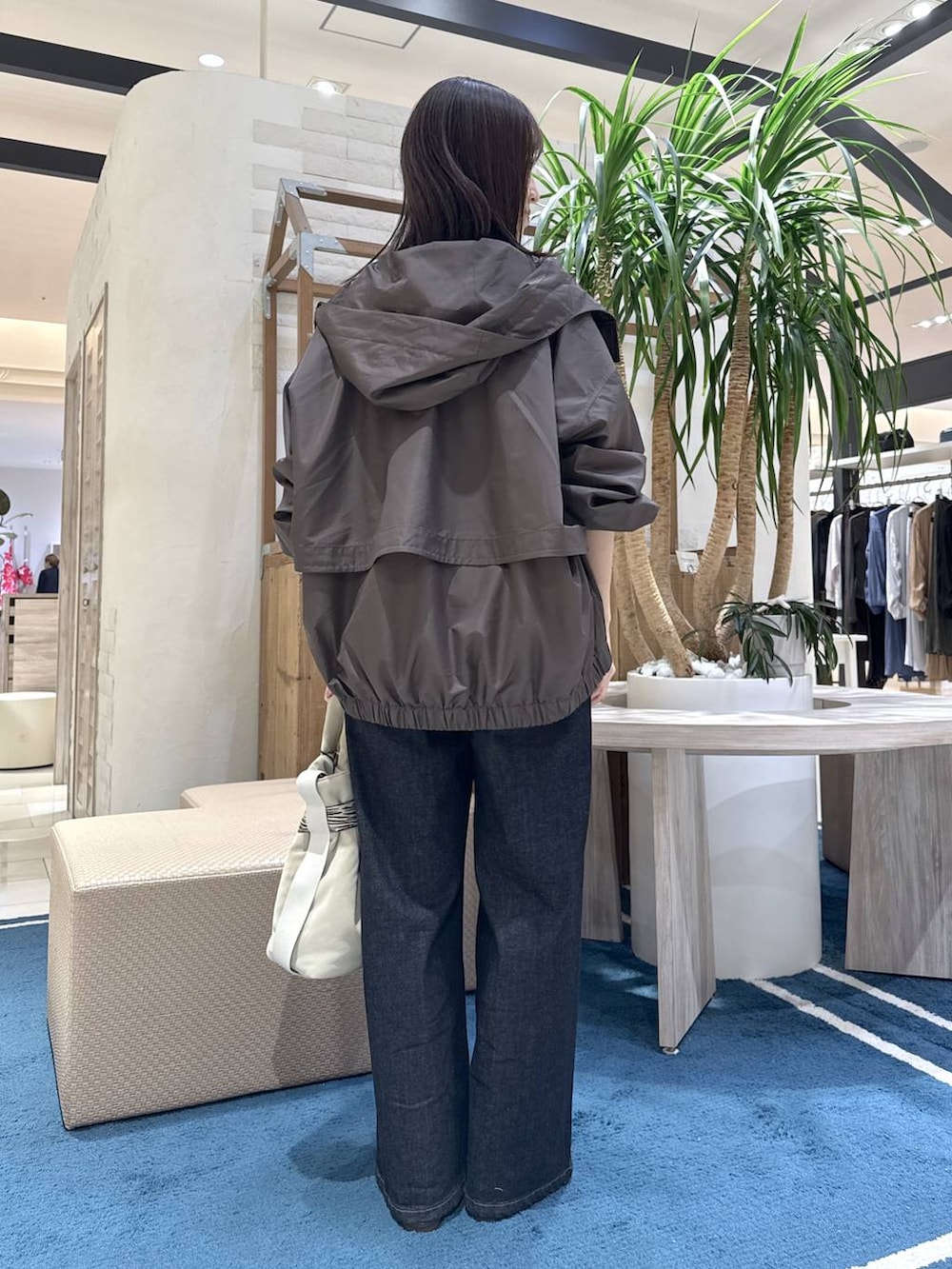 グレー系のトートバッグ、ブルー系のデニムパンツ、ホワイト系のニット/セーターを着用したレディースの秋コーディネートの3枚目の写真