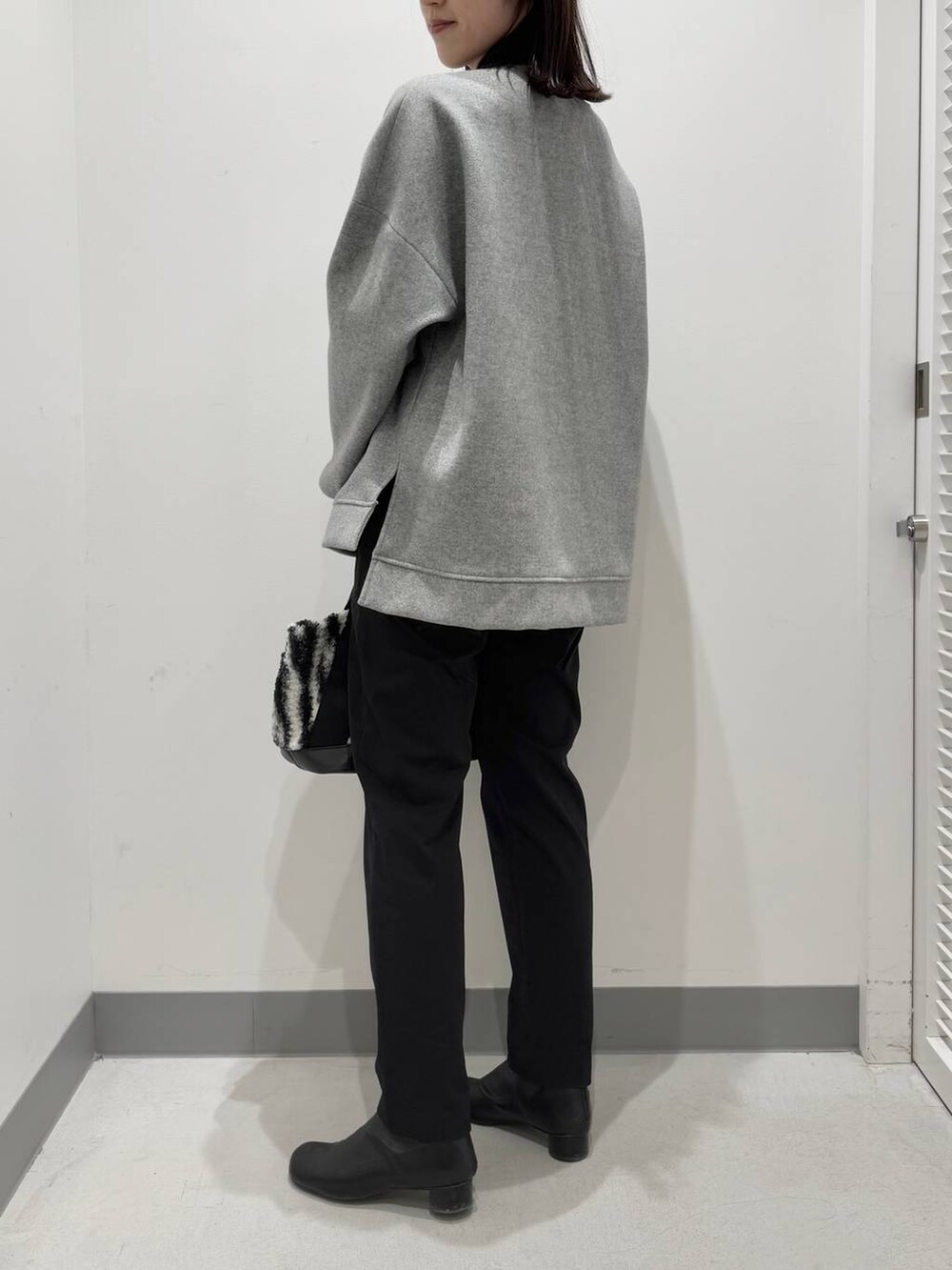 グレー系のパーカー、ホワイト系のトートバッグ、ブラック系のブーツを着用したレディースの冬コーディネートの3枚目の写真