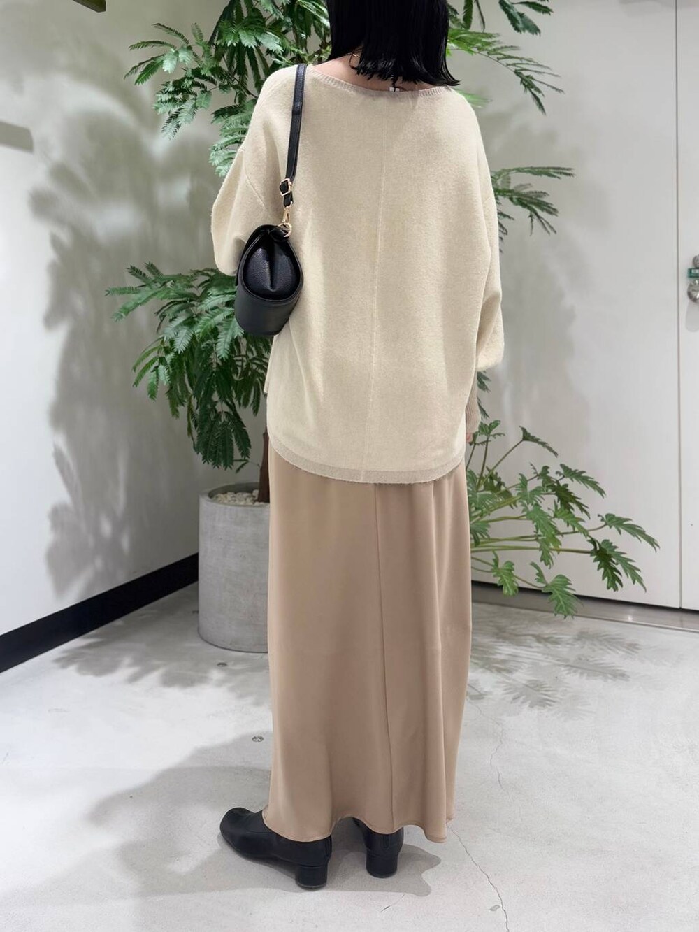 ブラック系のショルダーバッグ、ブラック系のブーツ、ホワイト系のニット/セーターを着用したレディースの冬コーディネートの3枚目の写真