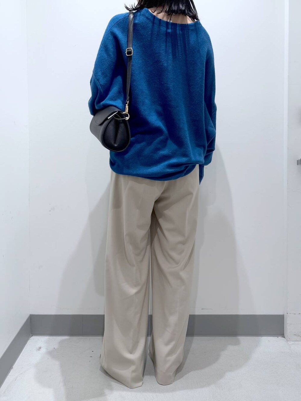 ブラック系のショルダーバッグ、ブラック系のブーツ、ブルー系のニット/セーターを着用したレディースの冬コーディネートの3枚目の写真