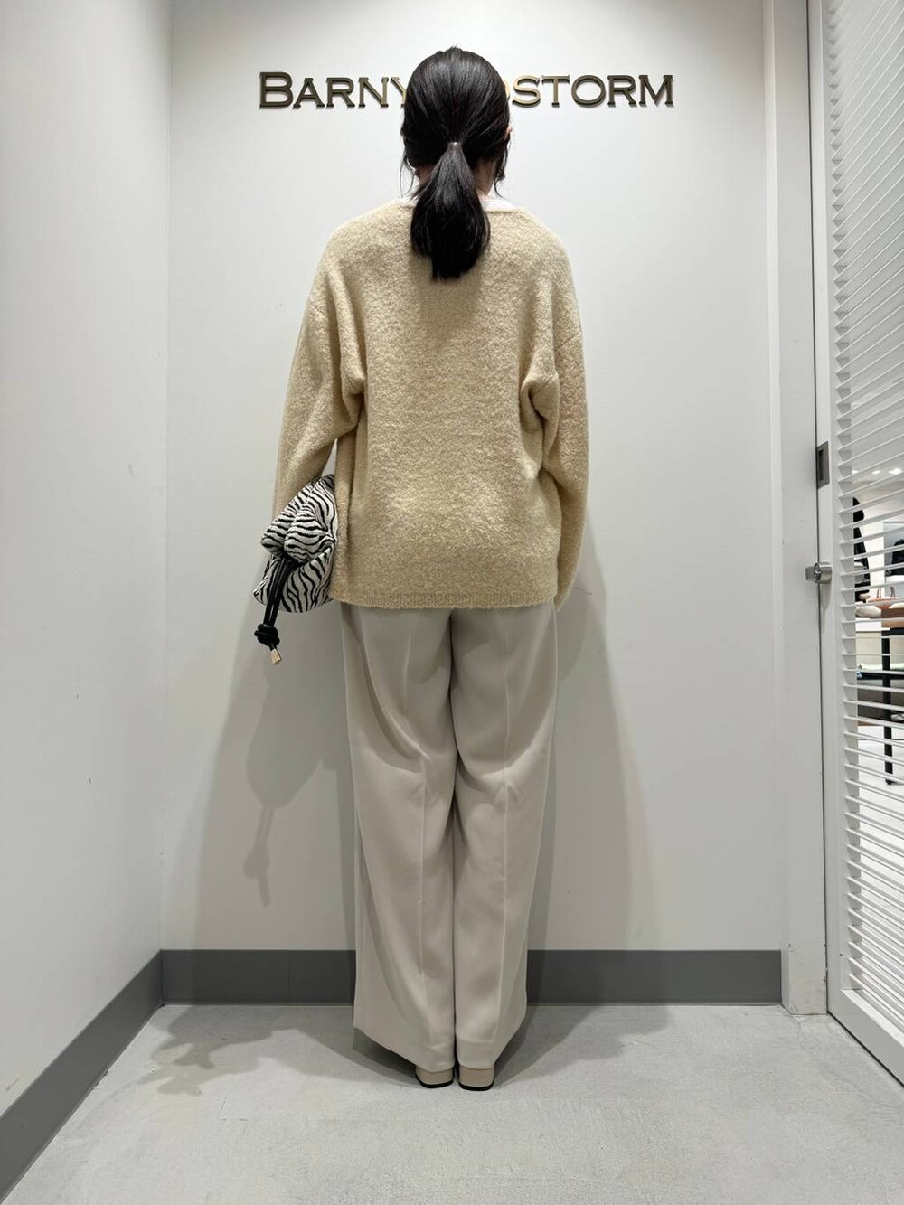 ホワイト系のブーツ、ホワイト系のスラックス、その他のショルダーバッグを着用したレディースの冬コーディネートの3枚目の写真