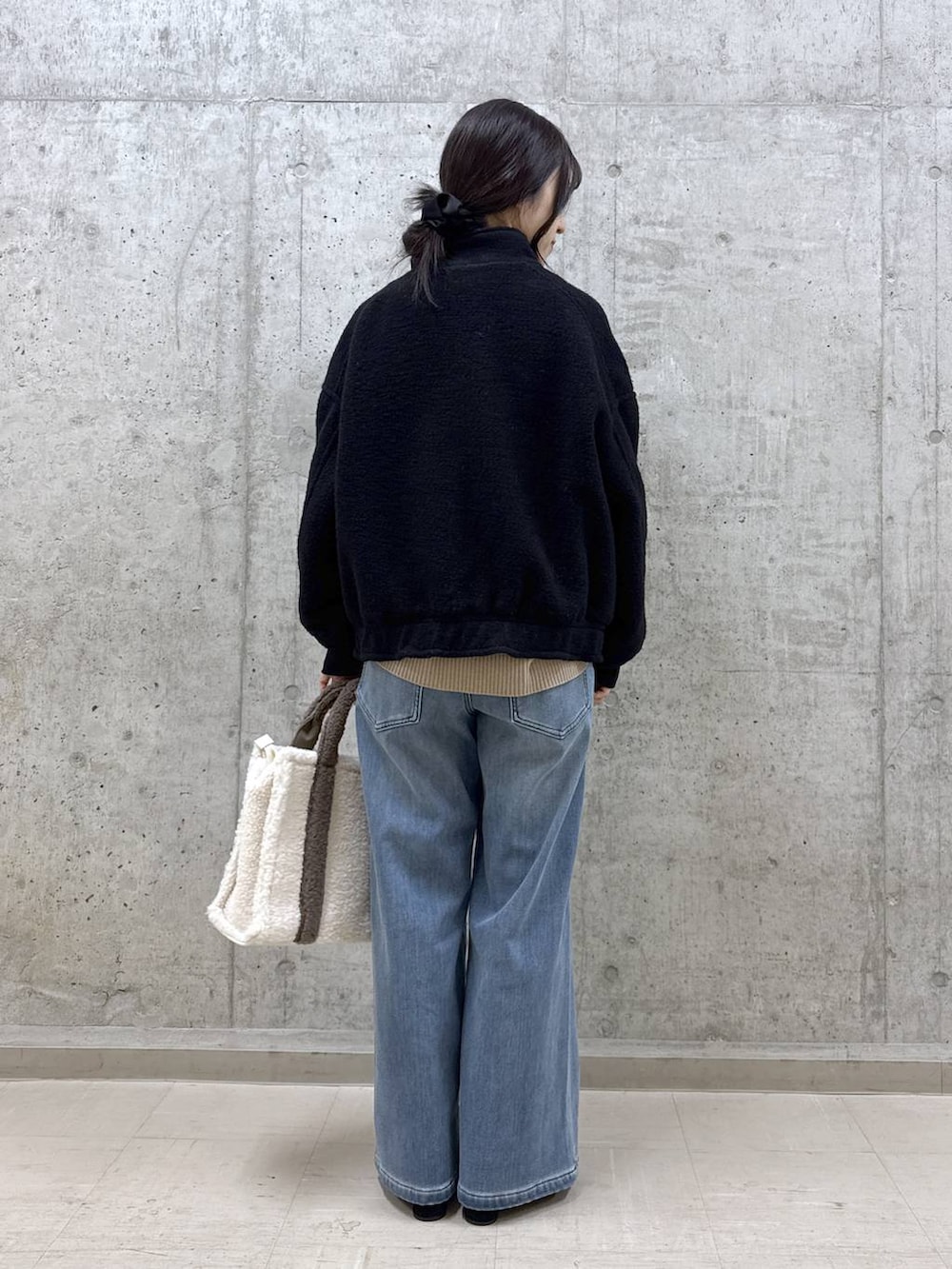 ベージュ系のニット/セーター、ブルー系のデニムパンツ、ブラック系のブルゾンを着用したレディースの秋コーディネートの4枚目の写真