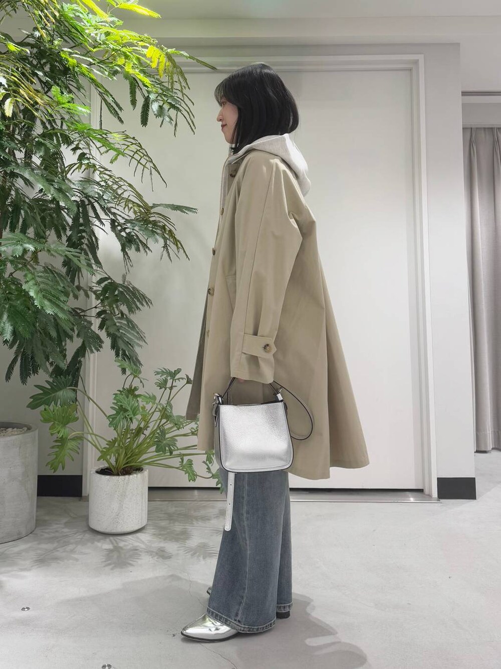 シルバー系のハンドバッグ、シルバー系のローファー、ブルー系のデニムパンツを着用したレディースの冬コーディネートの3枚目の写真