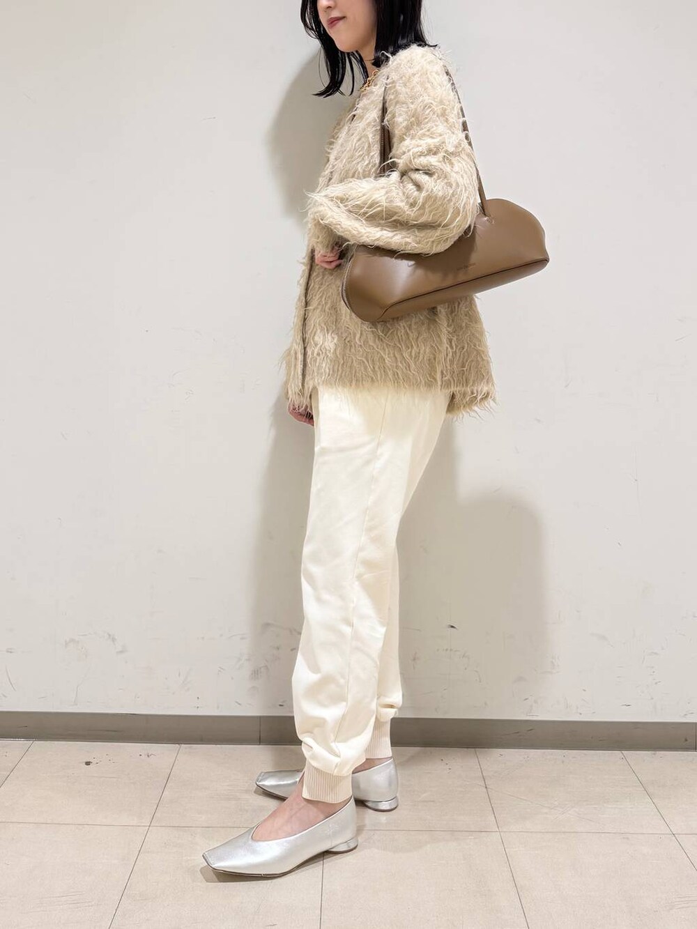 イエロー系のトートバッグ、シルバー系のパンプス、ベージュ系のカーディガン/ボレロを着用したレディースの冬コーディネートの2枚目の写真