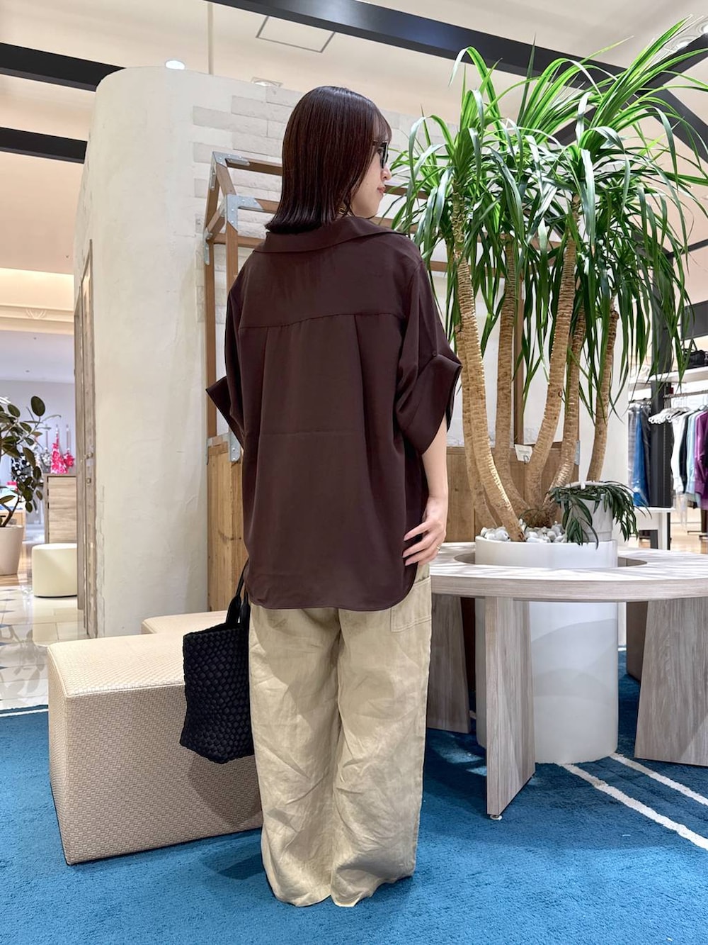 ブラック系のトートバッグ、ベージュ系のその他パンツ、ブラウン系のシャツ/ブラウスを着用したレディースの夏コーディネートの2枚目の写真