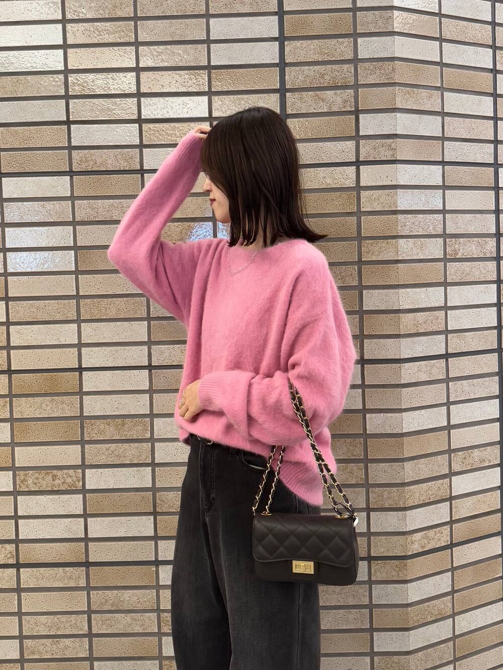 ピンク系のニット/セーター、ブラック系のデニムパンツ、ブラック系のブーツを着用したレディースの冬コーディネートの4枚目の写真