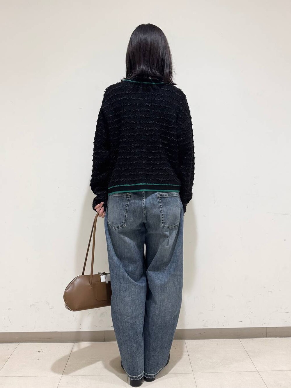 イエロー系のトートバッグ、ブルー系のデニムパンツ、ブラック系のブーツを着用したレディースの冬コーディネートの3枚目の写真