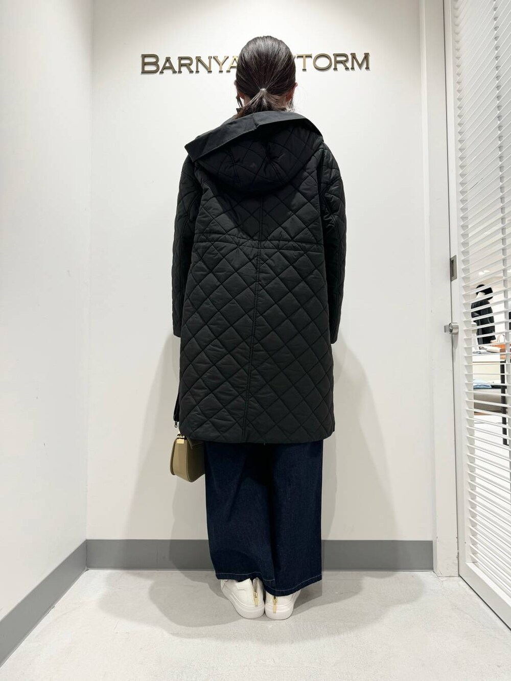 ブラック系のニット/セーター、ベージュ系のショルダーバッグ、ブラック系のダウンジャケット/コートを着用したレディースの冬コーディネートの3枚目の写真