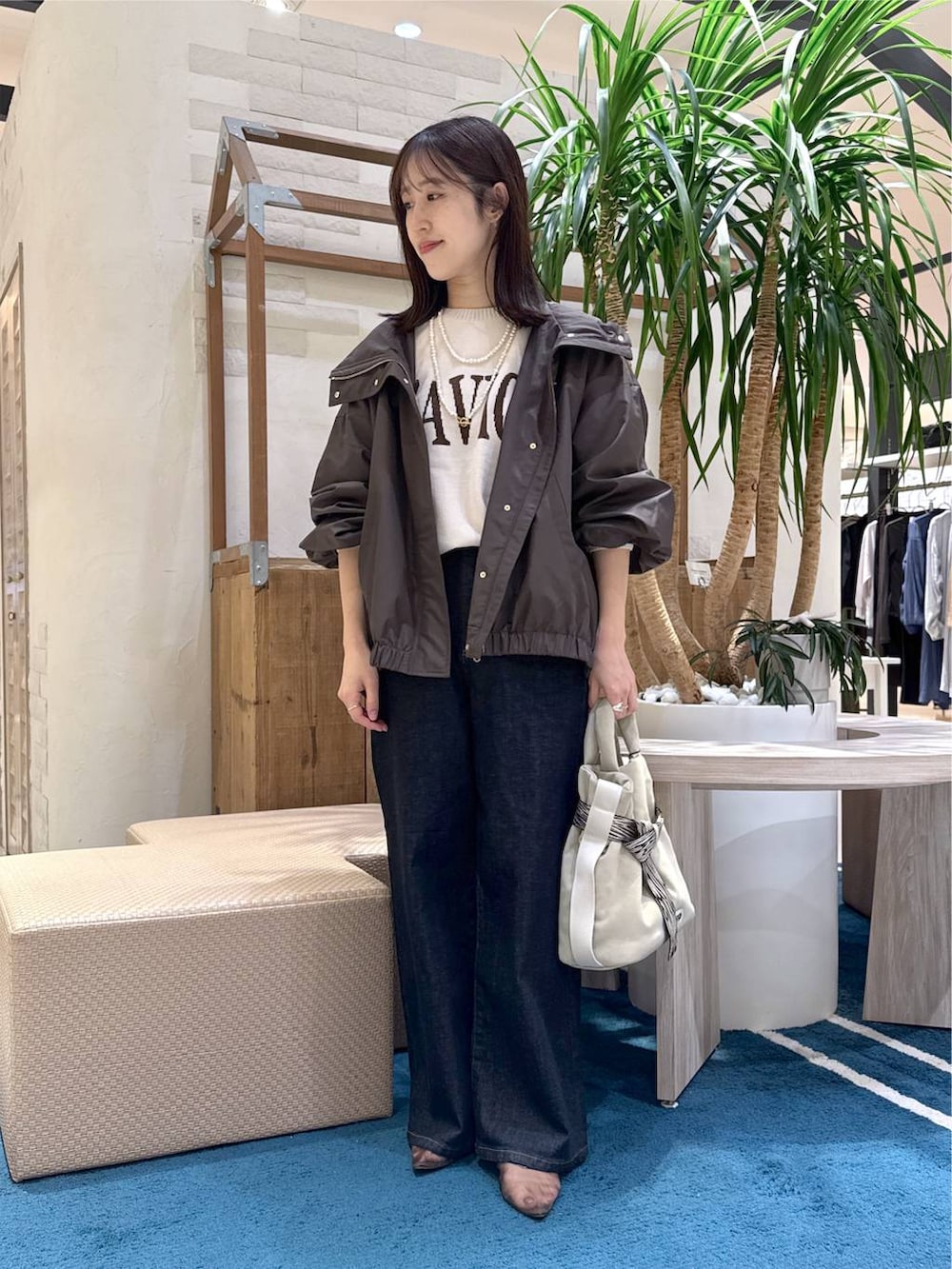 グレー系のトートバッグ、ブルー系のデニムパンツ、ホワイト系のニット/セーターを着用したレディースの秋コーディネートの6枚目の写真