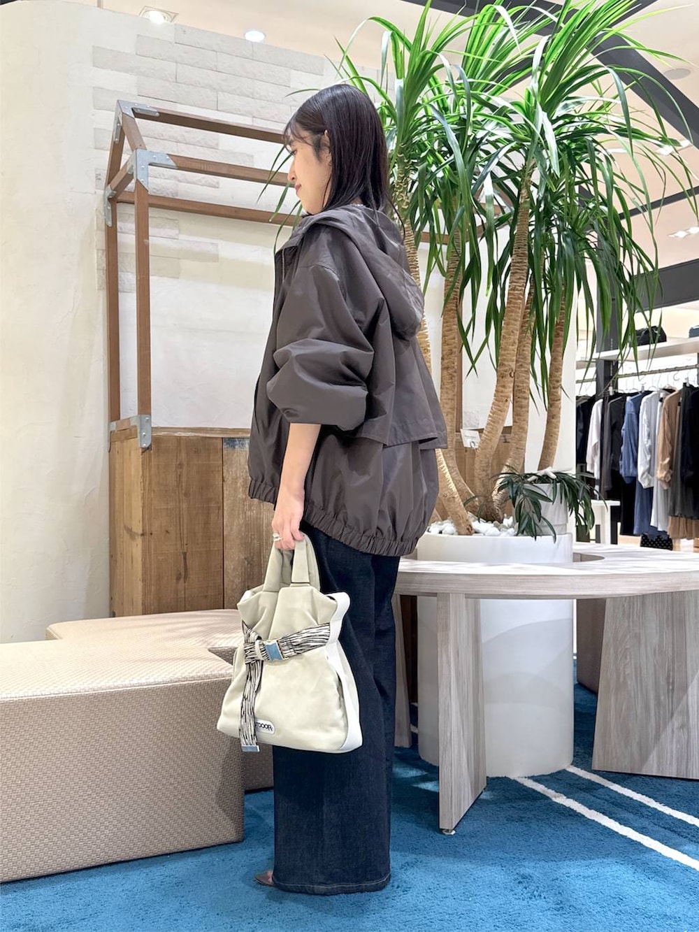 グレー系のトートバッグ、ブルー系のデニムパンツ、ホワイト系のニット/セーターを着用したレディースの秋コーディネートの2枚目の写真